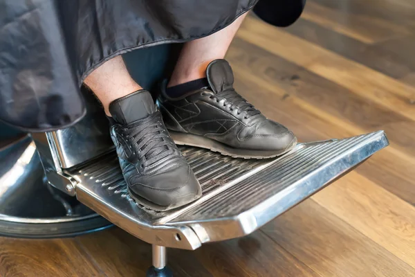 Patas de hombre en silla de barbero — Foto de Stock