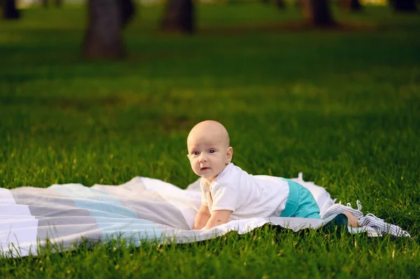 Little baby lying on grass in summer park — Stock Photo, Image