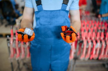 Bisiklet fabrikası, işçiler bisiklet yansıtıcıları gösteriyor. Üniformalı erkek tamirci bisiklet parçaları, atölyede montaj hattı, endüstriyel üretim
