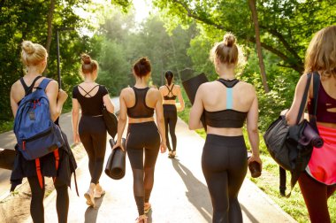 Paspaslı, arkası dönük, yaz parkında grup yoga eğitimi alan bir sürü kadın. Meditasyon, açık hava egzersizleri, rahatlama pratiği.