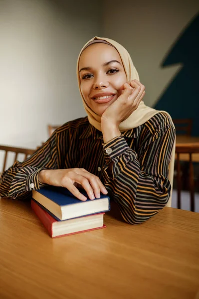ヒジャーブのアラブ女子学生は大学のカフェで教科書を持っている 図書館に座っている本を持つイスラム教徒の女性 — ストック写真