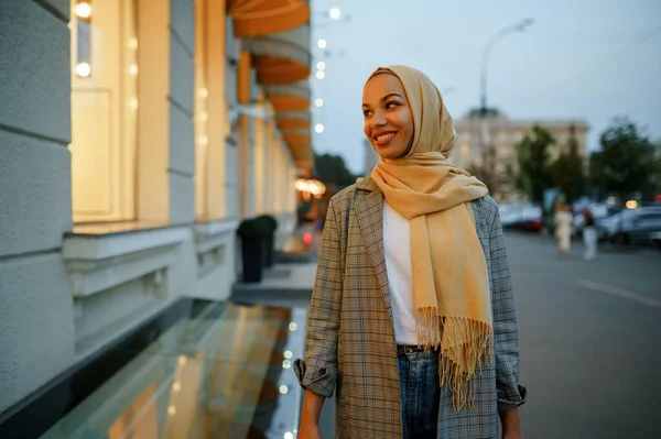 ダウンタウンのファッションストアのショーケースを探しているヒジャーブのアラブの女の子 ムスリム女性が通りを歩いている 大都市の女子学生 宗教と教育 — ストック写真