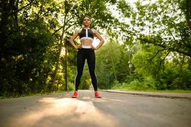 Sabah egzersizi, yaz parkında antrenman yapan bir kadın. Kadın koşucu güneşli bir günde spor için koşar, sağlıklı bir yaşam tarzı, açık havada koşar.