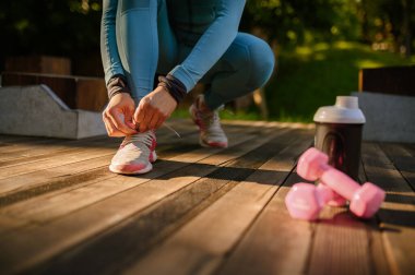 Parkta sabah antrenmanı, kulaklıklı gülümseyen bir kadın. Kadın koşucu güneşli bir günde spor için koşar, sağlıklı bir yaşam tarzı, açık havada spor eğitimi alan bir kız.