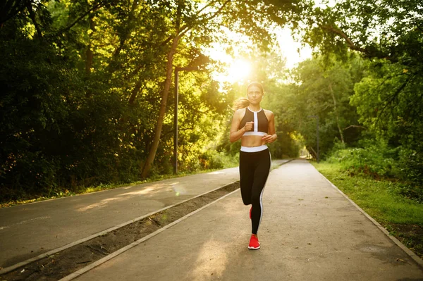 Morning run, woman on training in summer park. Female runner goes in for sports at sunny day, healthy lifestyle, jogger on outdoors workout