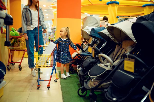 엄마와 가게에서 유모차를 아이들이 다니는 가게의 전시장 근처에 엄마와 귀여운 — 스톡 사진