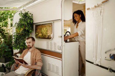 Karavanda aşk çifti, tekerlek üstünde macera, karavanda kamp. Karavanla seyahat eden erkek ve kadın, karavanda romantik tatiller, kamp arabasında boş vakitler.