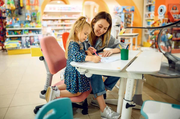 母親と赤ん坊は子供の店で絵を描く 子供の店でショーケースの近くのお母さんと愛らしい女の子 幸せな子供時代 家族は子供市場で購入します — ストック写真