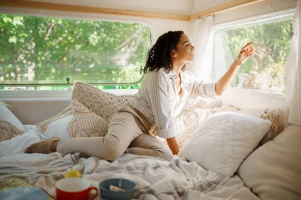 Smiling woman relax in bed, camping in a trailer. Couple travels on van, romantic vacations on motorhome, camper leisures in camping-car