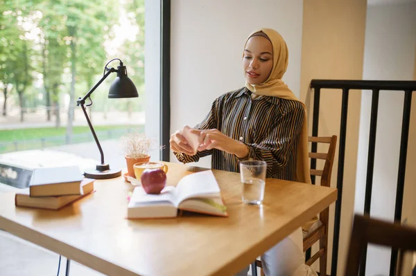 アラブの女の子は 大学のカフェでコーヒーとカップの写真を撮ります トップビュー 図書館に座っている本を持つイスラム教徒の女性 — ストック写真