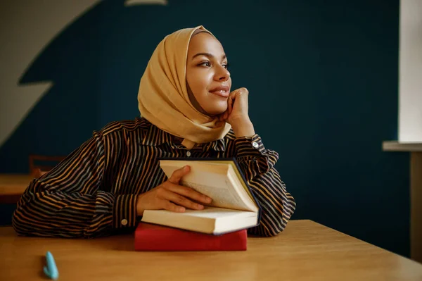 ヒジャーブのアラブ女子学生は大学のカフェで教科書を持っている 図書館に座って本を持つイスラム教徒の女性 宗教と教育 — ストック写真