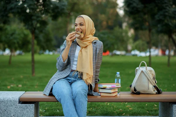 夏の公園のベンチに座っているアラブ女性学生 イスラム教徒の女性は歩く道に休んでいる 宗教と教育 — ストック写真