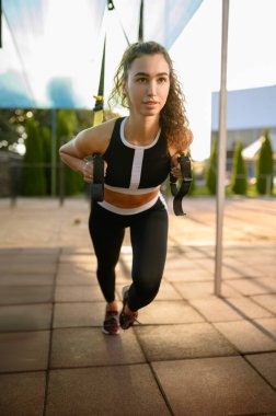 Dışarıda spor alanında esneme egzersizi yapan bir kadın. Spor giyim sektöründe zayıf bir kadın, spor salonu dışında egzersiz, formda.