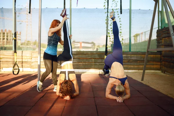 Women doing balance exercise with instructor on sports ground outdoors, group fitness training outside. Slim female athletes in sportswear, team fit workout, teamwork