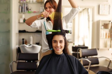 Kuaför kıvırcık saçlar, taraklar kadın saçı, kuaför salonu. Kuafördeki stilist ve müşteri. Güzellik sektörü, profesyonel hizmet.