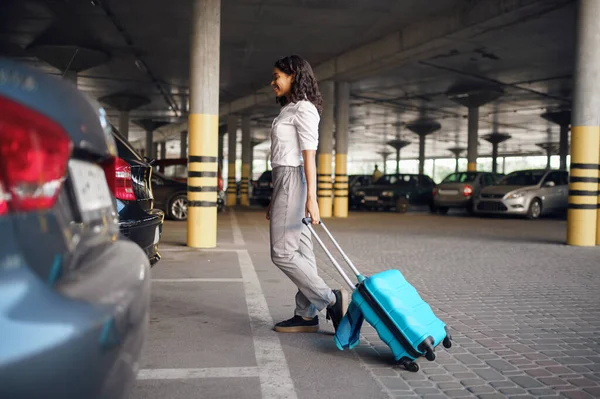 駐車場でスーツケースを着た若い女性 駐車場で荷物を持つ女性旅行者 袋を持つ乗客 車の近くに荷物を持つ女の子 — ストック写真