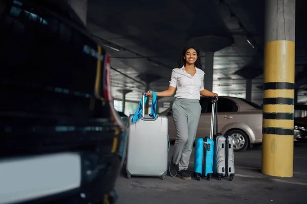 駐車場で多くのスーツケースを持つ幸せな女性 駐車場で荷物を持つ女性旅行者 袋を持つ乗客 車の近くに荷物を持つ女の子 — ストック写真