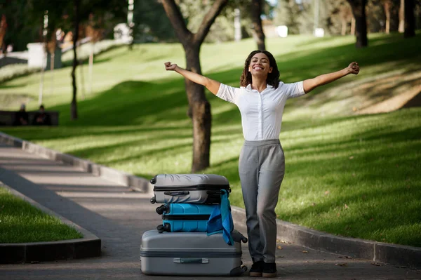 夏の公園を歩くスーツケース付きの陽気な女性 荷物レジャー屋外で女性の旅行者は 袋を自然の中で休んで乗客 荷物のある女の子は街の路地でリラックス — ストック写真