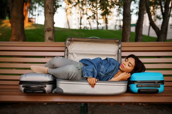 公園のベンチで開かれたスーツケースで寝ている若い女性 荷物レジャー屋外で女性の旅行者は 袋を自然の中で休んで乗客 荷物のある女の子は街の路地でリラックス — ストック写真