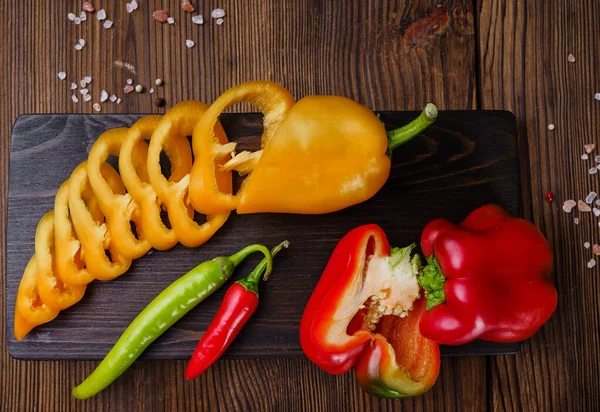 Güvertede taze kesilmiş biber, ahşap arka planda üst manzara. Organik vejetaryen yiyecekler, market çeşitleri, doğal ürünler, sağlıklı yaşam tarzı konsepti.