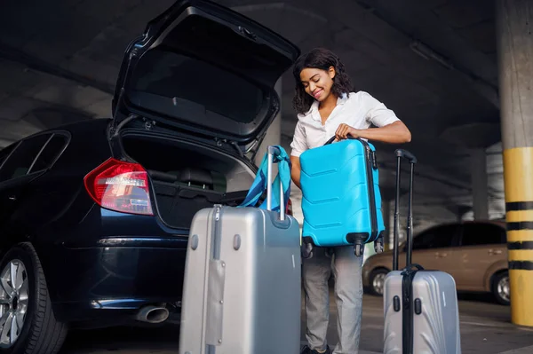 駐車場で多くのスーツケースを持つ幸せな女性 駐車場で荷物を持つ女性旅行者 袋を持つ乗客 車の近くに荷物を持つ女の子 — ストック写真