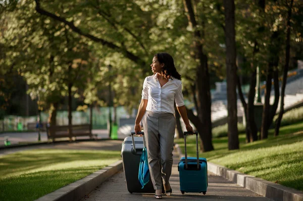 夏の公園の歩道に2つのスーツケースを持つ女性 荷物レジャー屋外で女性の旅行者は 袋を自然の中で休んで乗客 荷物のある女の子は街の路地でリラックス — ストック写真