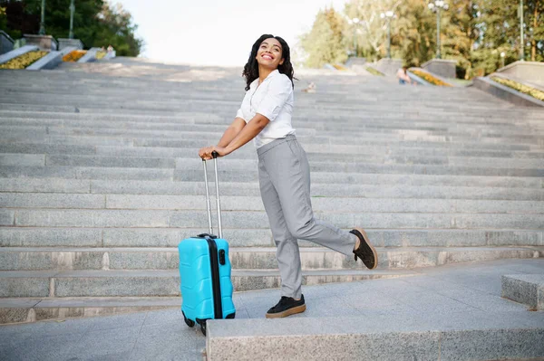在夏季公园的楼梯上 快乐的女人摆出一副提着手提箱的姿势 携带行李的女旅客在户外休息 携带行李的旅客在大自然中休息 带着行李的女孩在市区小巷里休息 — 图库照片