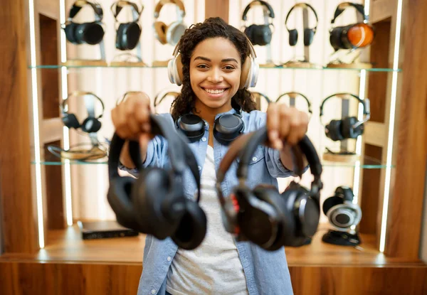 女人在音响器材商店里放耳机 音乐爱好者 音乐商店里的女性 背景上有耳机的橱窗 多媒体沙龙里的买家 — 图库照片