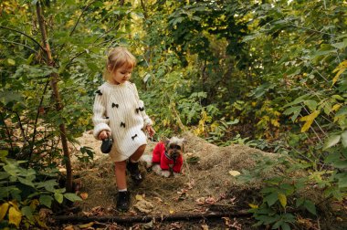 Komik köpekli bir çocuk ormanda yürüyor, en iyi arkadaşlar. Açık havada köpek yavrusu olan bir kız. Küçük kız ve evcil hayvanı dışarıda ilginç bir macera yaşıyorlar, mutlu bir çocukluk.