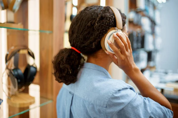 在音响店试戴耳机的女人 后视镜 音像店的女店员 背对着耳机的陈列柜 多媒体沙龙的买主 — 图库照片