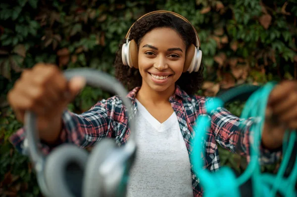 夏の公園で音楽を聴くヘッドフォンの音楽ファン 屋外を歩く女性のオーディオフィルム イヤホンの女の子 背景に緑の茂み — ストック写真