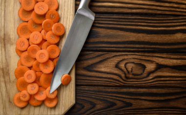 Tahta arka planda taze kesilmiş havuç ve bıçak. Organik vejetaryen yiyecekler, market çeşitleri, doğal eko ürünler, sağlıklı yaşam tarzı konsepti.