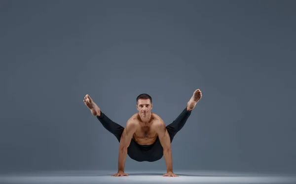 男性ヨガはスタジオでストレッチ運動をします 灰色の背景 アサナトレーニング トップ濃度 健康的なライフスタイルを練習強い男 — ストック写真