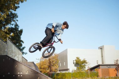 Erkek BMX motorcusu, harekete geçti, paten parkında eğitim gören bir genç. Aşırı bisiklet sporu, tehlikeli bisiklet egzersizi, sokak sürme riski, yaz parkında bisiklet sürme