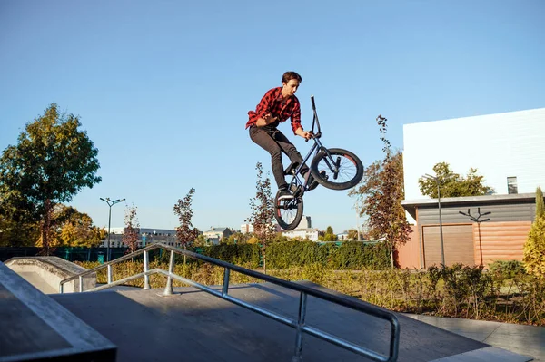 Male bmx biker, jump in action, teenager on training in skatepark. Extreme bicycle sport, dangerous cycle exercise, risk street riding, biking in summer park