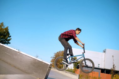 Bmx motorcusu merdivenlerde numara yapıyor, genç kız kaykay parkında eğitim görüyor. Aşırı bisiklet sporu, tehlikeli bisiklet egzersizi, sokak sürme riski, yaz parkında bisiklet sürme
