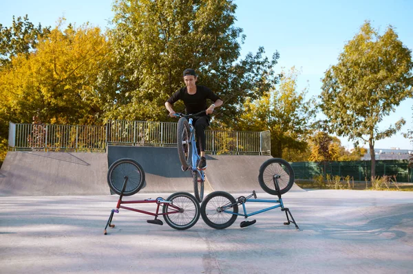 Bmx bikers lifestyle, training in skatepark. Extreme bicycle sport, dangerous cycle exercise, street riding, teen biking in summer park