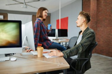 Erkek ve kadın bilişim uzmanları ofiste konuşuyor