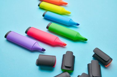 Mavi arkaplanda açık renkli kalıcı kalemler var. Ofis kırtasiye malzemeleri, okul veya eğitim aksesuarları, yazı ve çizim araçları