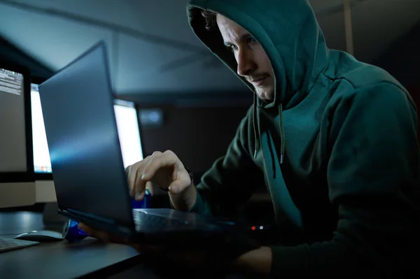 Hacker de internet masculino no capuz funciona no laptop — Fotografia de Stock