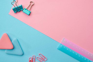Ataç ve cetvel yakın plan, mavi ve pembe arka plan. Ofis kırtasiye malzemeleri, okul veya eğitim aksesuarları, yazı ve çizim araçları