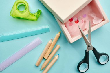 Ofis malzemeleri, yakın plan, mavi arka plan. Okul veya eğitim aksesuarları, yazma ve çizim araçları, kalem ve cetvel, makas ve koli bandı