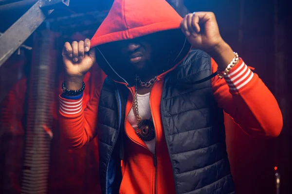 Rapper in red hoodie poses in grunge studio — Stock Photo, Image