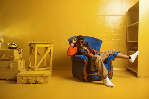 Rapper posando em cadeira em estúdio com tons amarelos — Fotografia de Stock