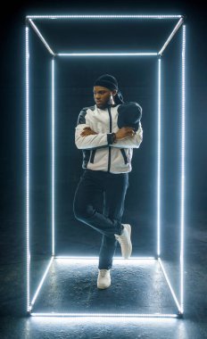 Aydınlatılmış küp, karanlık arka planda poz veren rapçi. Hip-hop sanatçısı, rap şarkıcısı, break dans performansı, eğlence yaşam tarzı, break dans