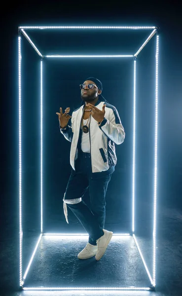 Rapper w okularach przeciwsłonecznych pozuje w podświetlanej kostce — Zdjęcie stockowe