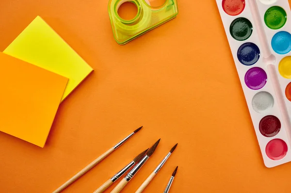 Akvarell Färger Borstar Och Anteckningsblock Närbild Orange Bakgrund Kontorsmateriel Skol — Stockfoto