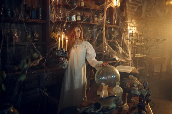Mumlu korkunç kadın iksirlerin yanında duruyor.