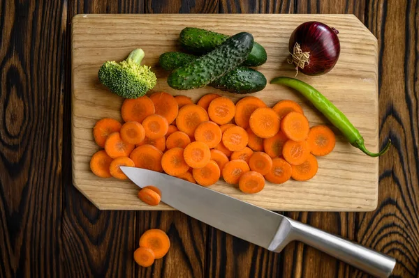 Légumes coupés et couteau, fond en bois — Photo