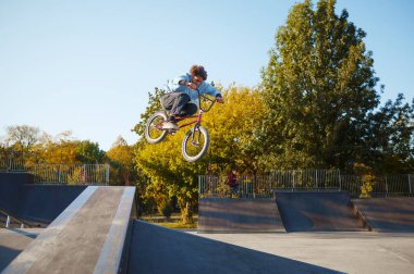 Bmx motorcusu kaykay parkında tırabzan kullanarak gidiyor.